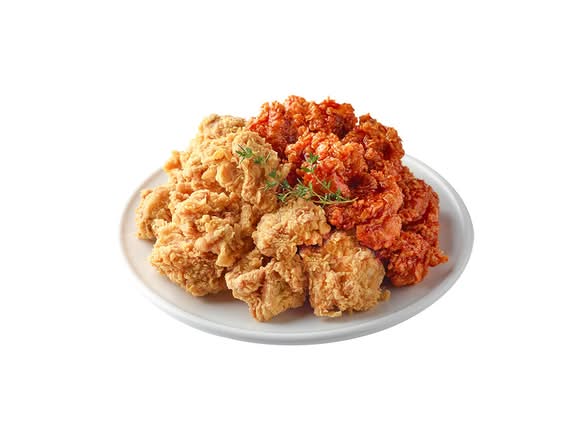 Boneless chicken, half original crispy and half sauced, on a white plate
